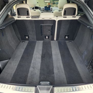 Clean and spacious car trunk with dark carpeting and rear seats.