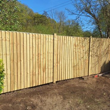 Newly installed wooden fence under clear blue sky.