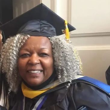 Woman in graduation cap and gown smiling at ceremony.