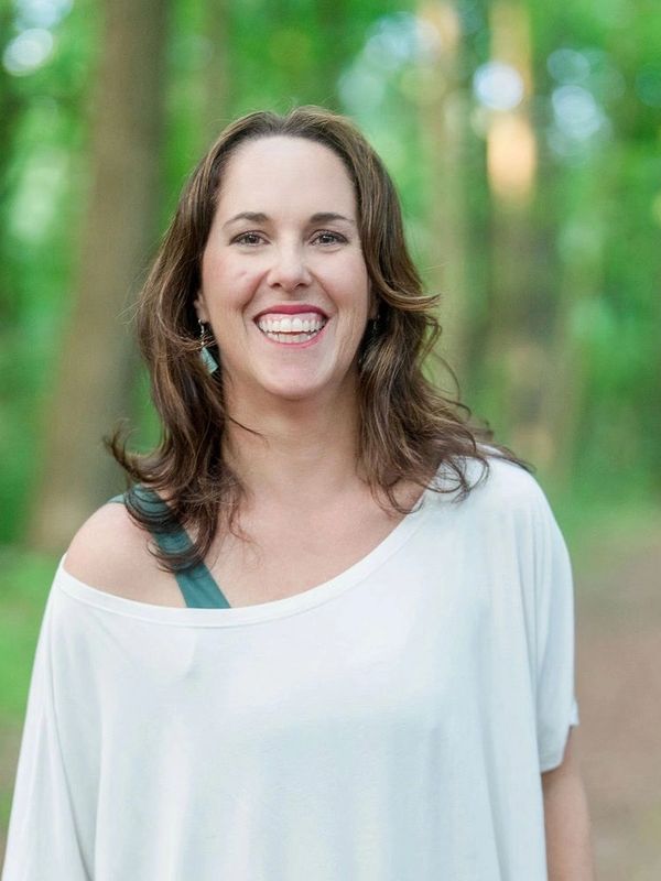 Smiling woman in white top outdoors.