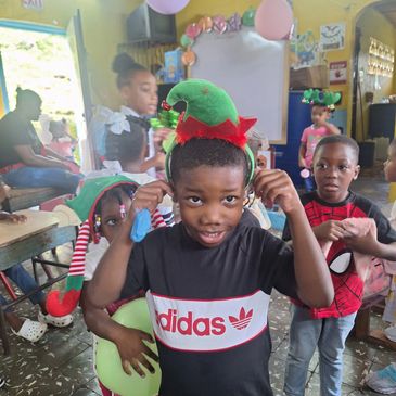 Children in festive hats celebrating indoors with balloons and decorations.