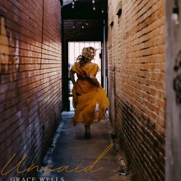 A woman in a yellow dress runs down a narrow brick alley toward a bright exit.