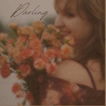 A woman holding a bouquet of orange flowers, softly smiling.