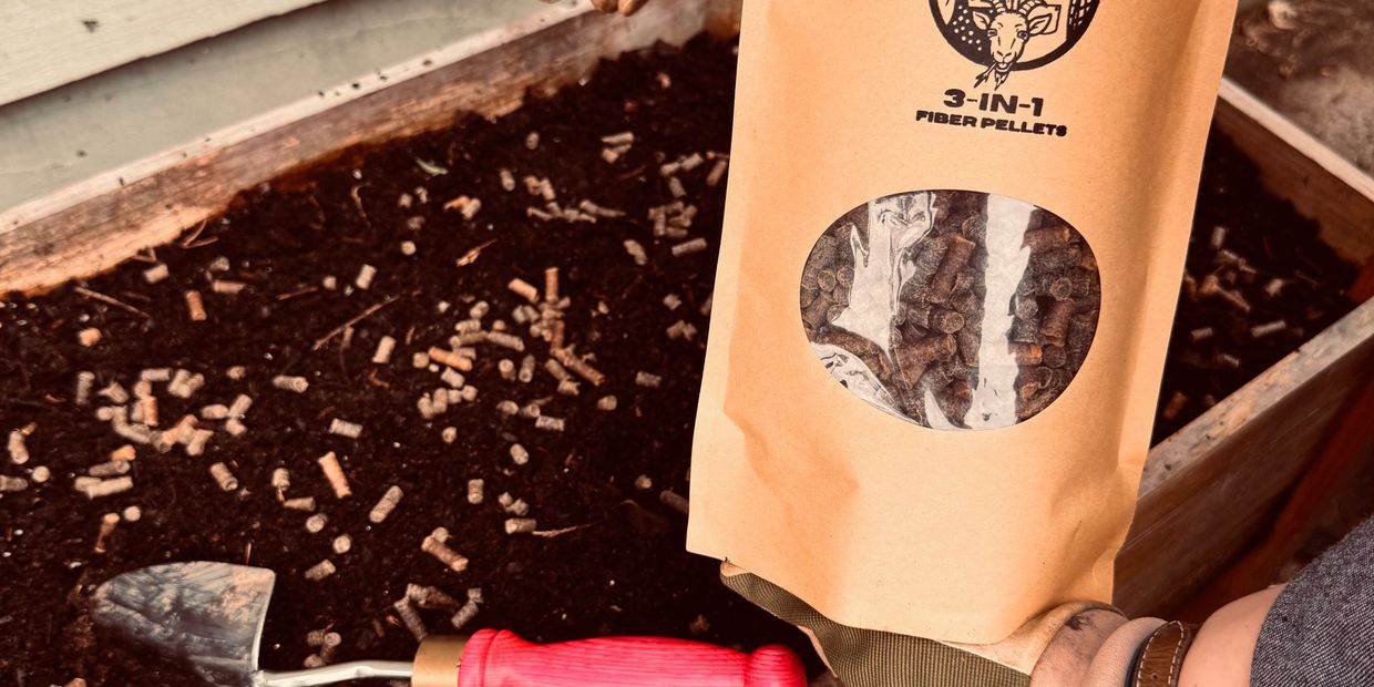 Bag of 3-in-1 fiber pellets held over soil with gardening trowel.