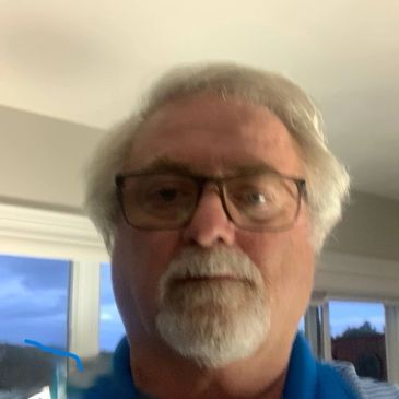 Elderly man with glasses and white hair indoors.