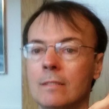 Close-up portrait of a man wearing glasses indoors.