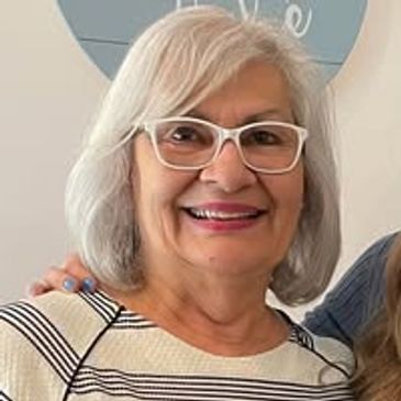 Smiling elderly woman with white hair and glasses.