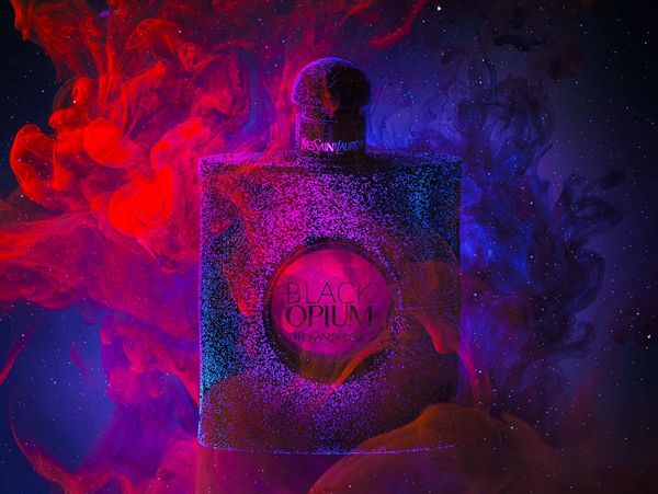 Black Opium perfume with colorful smoke background.