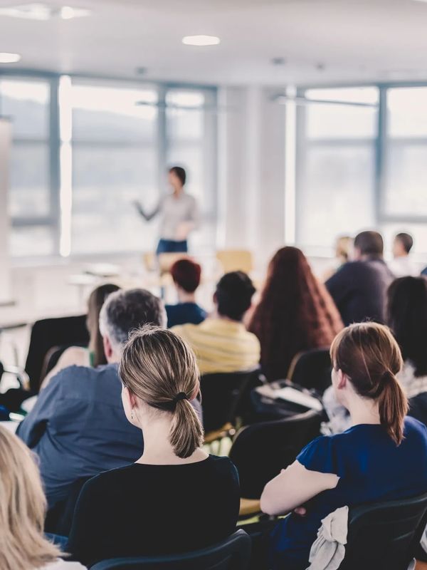 A classroom with students and a presenter teaching with the aid of a projected display