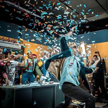 Person joyfully throwing confetti in a lively indoor party.
