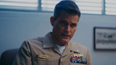 A man in a military uniform talking in an office.