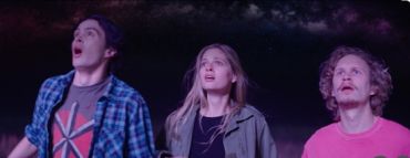 Three young people looking up in awe at the night sky.