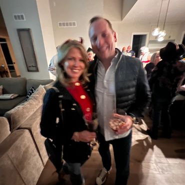 Smiling couple holding drinks at a party indoors.