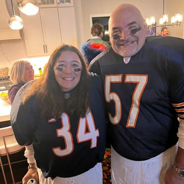 Two people smiling in sports jerseys with face paint.