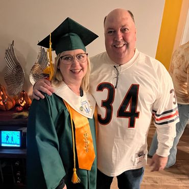 Graduate in cap and gown with a smiling man in a sports jersey.