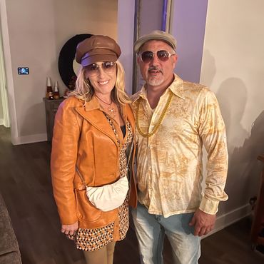 Couple dressed in retro 70s-style outfits indoors.