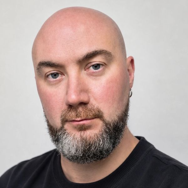 Portrait of a bald man with a salt-and-pepper beard and blue eyes.