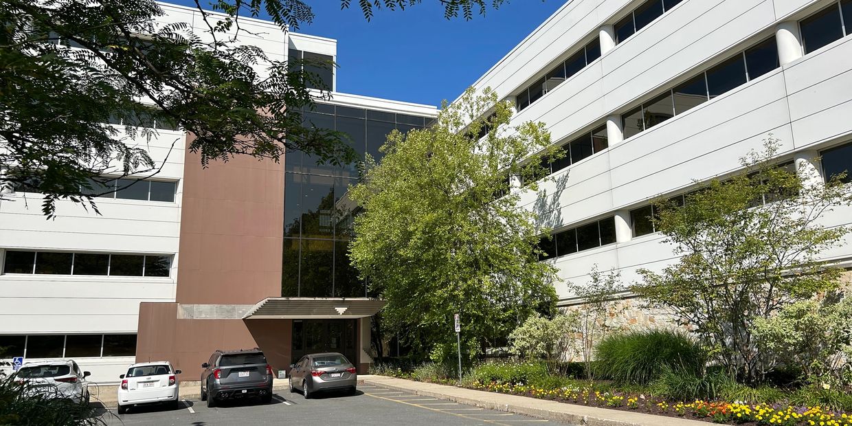 a large office building with cars parked out front and trees