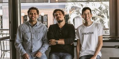 Three men posing indoors, smiling.