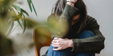 Woman sitting with head down looking distressed.
