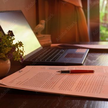 Ordinateur sur un bureau, feuillet avec stylo rouge.