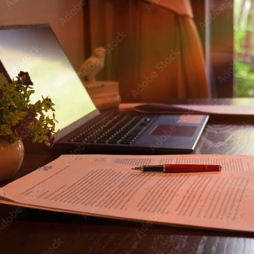 Ordinateur sur un bureau, feuillet avec stylo rouge.