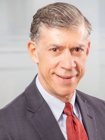 Professional middle-aged man in a suit and red tie smiling.