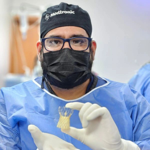 Médico con equipo quirúrgico sostiene implante.