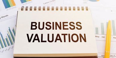 A notepad with 'Business Valuation' text surrounded by charts and a pen.
