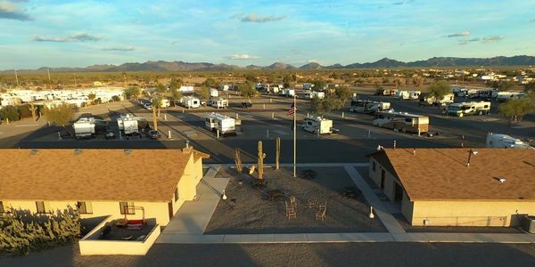 A spacious RV park with many trailers under a clear sky and mountains in the background.