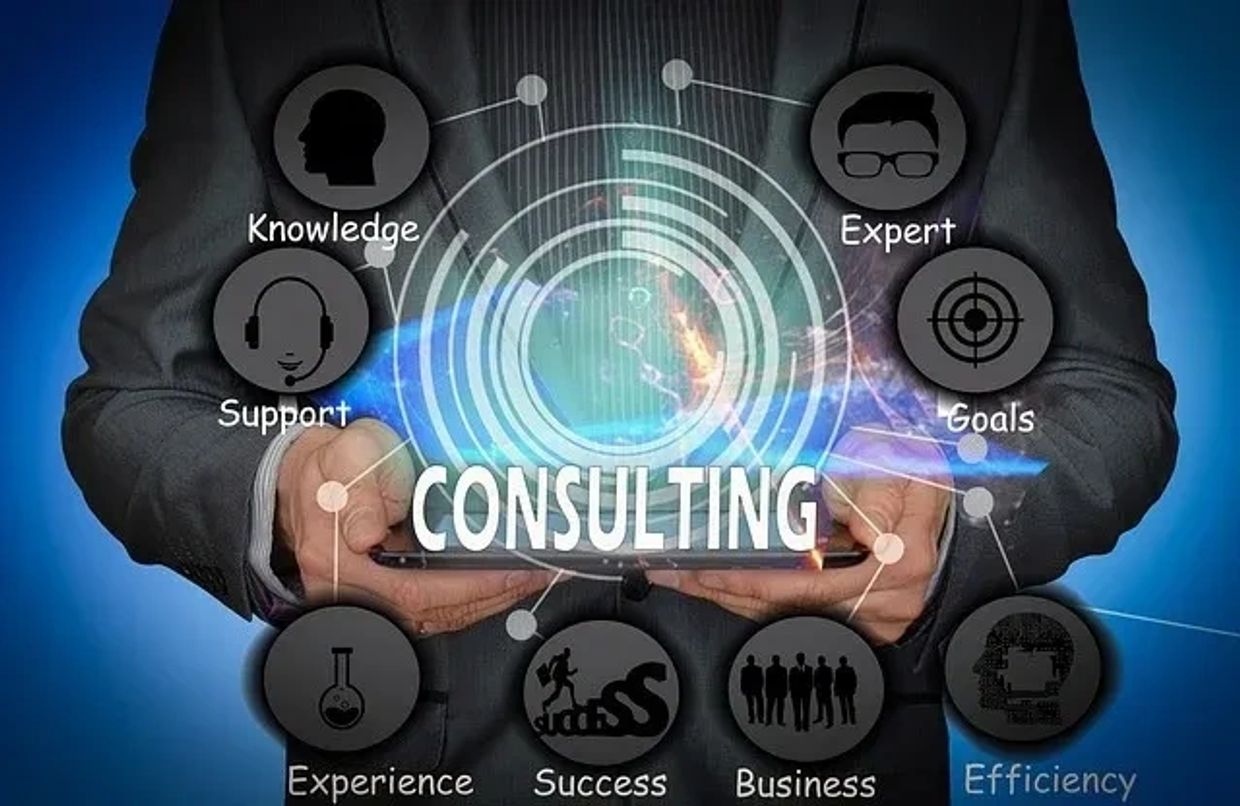 A businessman holding a tablet with consulting-related icons and words.