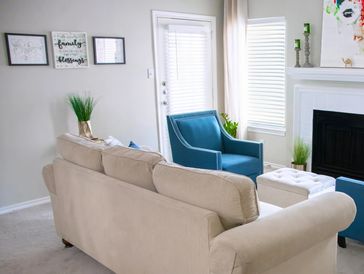 Cozy living room with beige sofa, blue chairs, and modern fireplace.