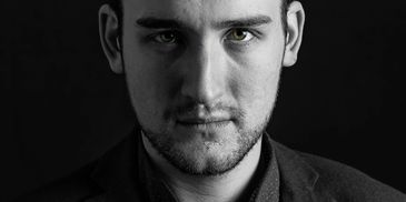 Black and white portrait of a man with striking green eyes.