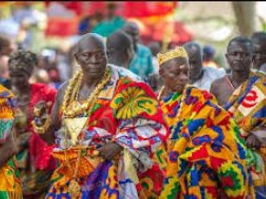 African men wearing colorful traditional kente cloth and gold jewelry.