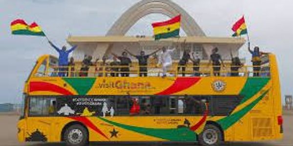 People celebrating on a colorful double-decker bus with Ghana flags.