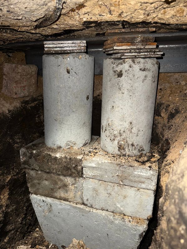 Two cylindrical concrete piers with metal shims supporting a structure above.
