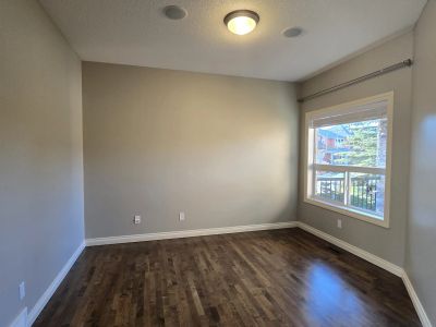 Empty room with hardwood flooring and a window letting in natural light.