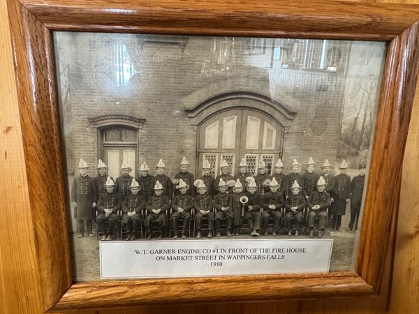 Vintage photo of firefighters posing in front of a firehouse in 1910.
