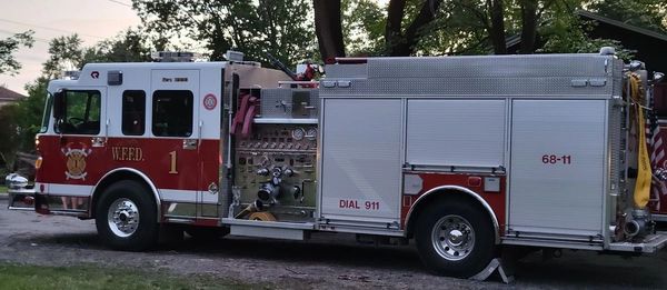 A red and white fire truck parked outdoors near trees.