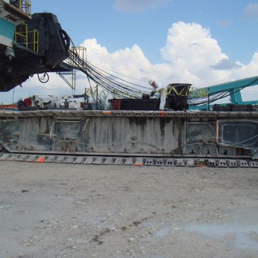 Worker in protective suit inspecting a large industrial machine outdoors.