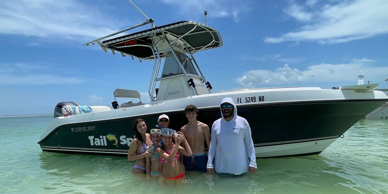 Guests posing next to TailSpin during their private charter to the Islamorada Sandbar. 