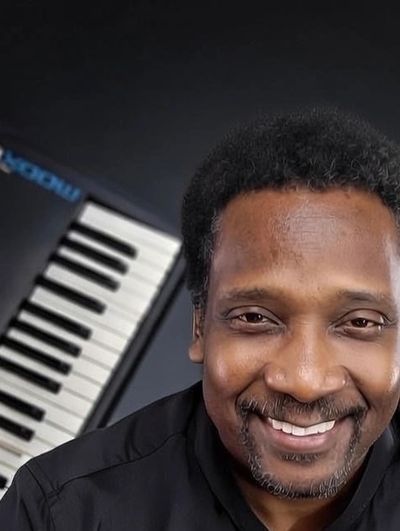 Smiling man with a keyboard in the background.