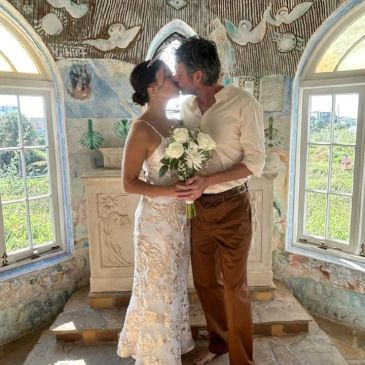 Couple kissing during intimate wedding ceremony in rustic chapel.