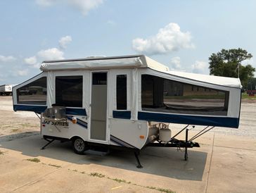 Pop-up camper trailer with extended sides parked on concrete.