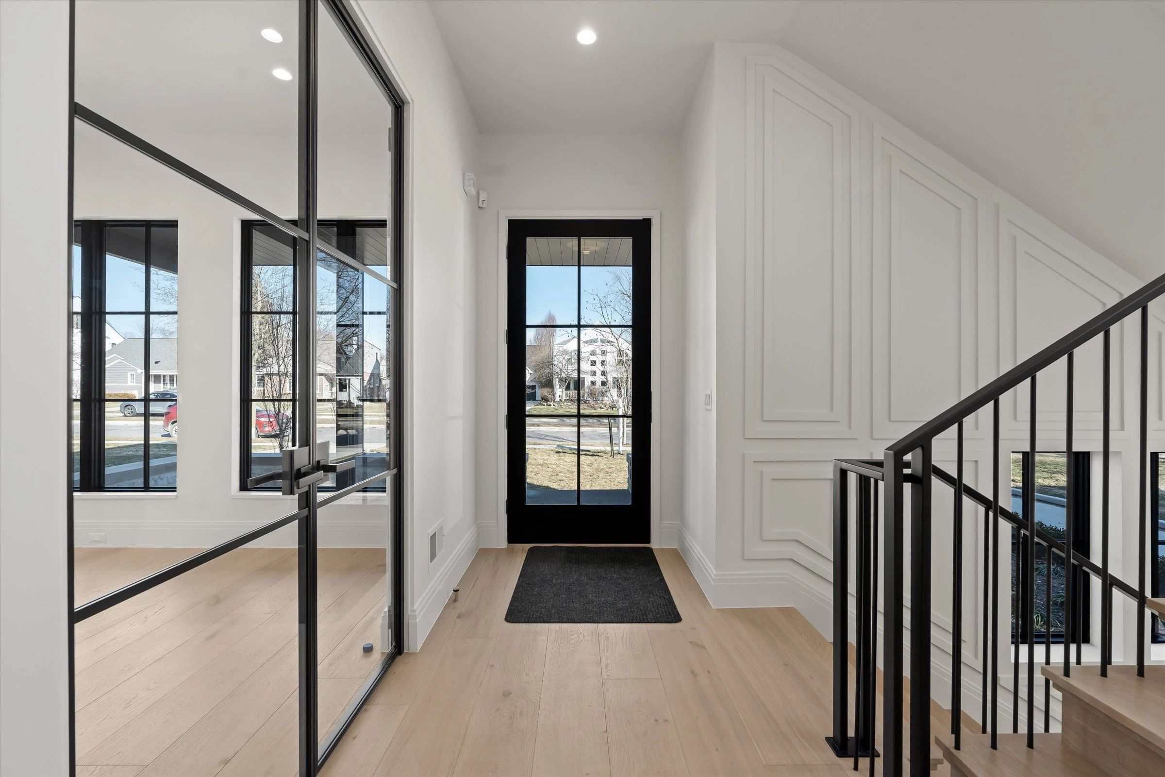Modern entryway with black-framed glass door and light wood flooring.