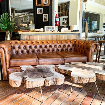 Brown leather sofa with rustic wooden coffee tables in a cozy living room.