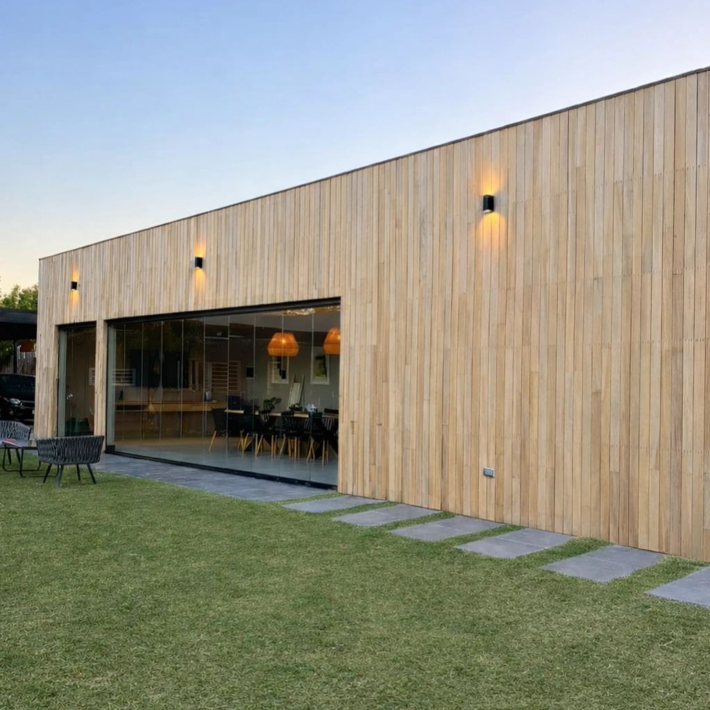 Modern wooden house exterior with large glass windows and a green lawn.