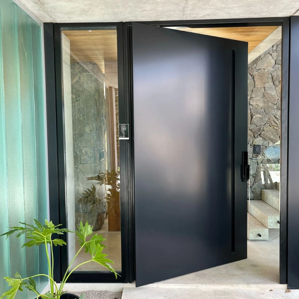 Modern black pivot door with glass side panels in a stylish entrance.