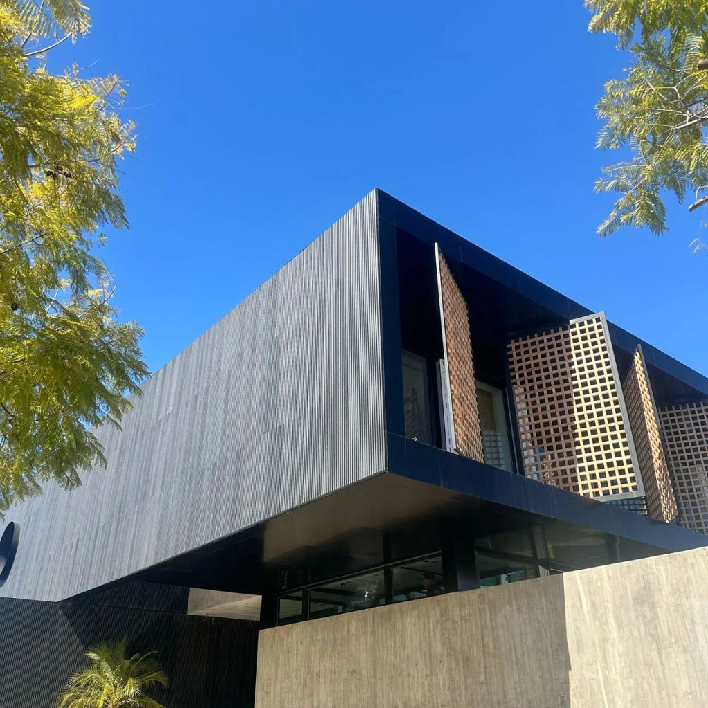 Modern building with geometric design and lattice window panels under a clear blue sky.