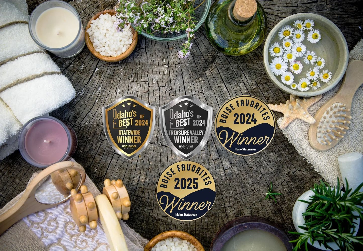 A rustic spa setup with candles, towels, flowers, and award badges on a wooden surface.